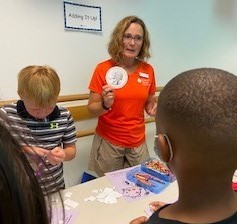 Amy F quizzes the campers at Camp Canton on their coin knowledge: identification and value.